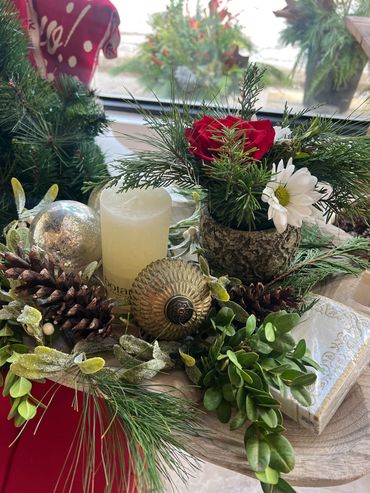 Festive holiday centerpiece with candle and flowers.