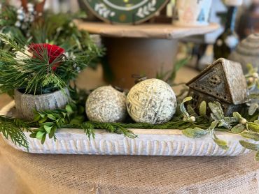 Decorative holiday centerpiece with greenery and rustic house.