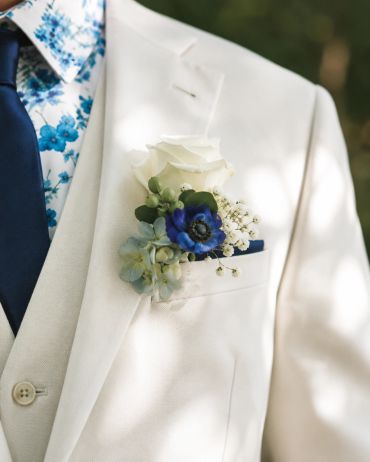 White suit with a floral boutonniere.