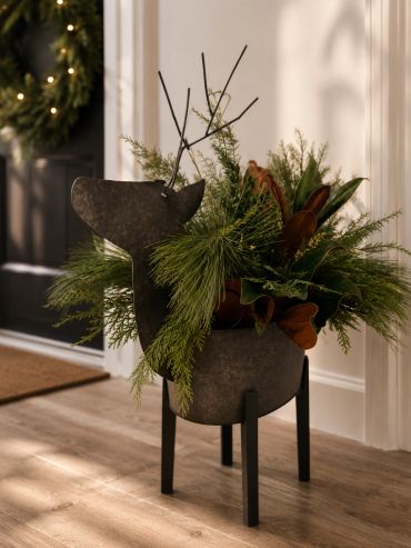 Metal reindeer planter with greenery by a doorway.