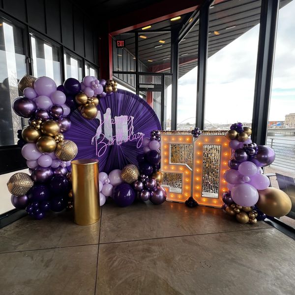 Purple and gold balloon arrangement celebrating a 50th birthday by the river.
