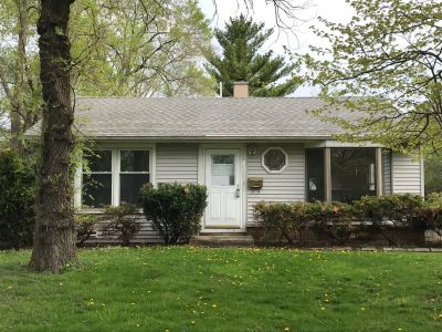 Small single-story house surrounded by trees and bushes.