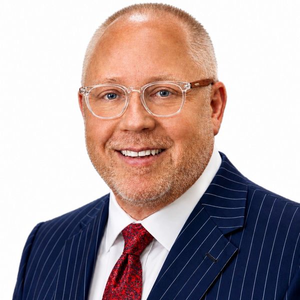 Smiling man in a suit and glasses.
