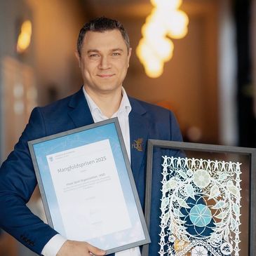 Man in suit holding framed award and certificate.