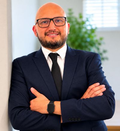 Confident bald man in a suit with glasses smiling.