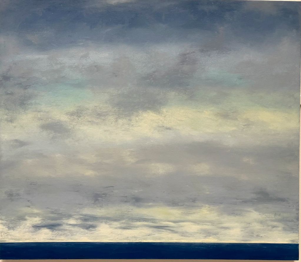 A serene seascape with a cloudy sky and calm ocean horizon.