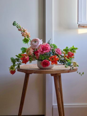 Colorful flower arrangement on a wooden table in soft natural light.