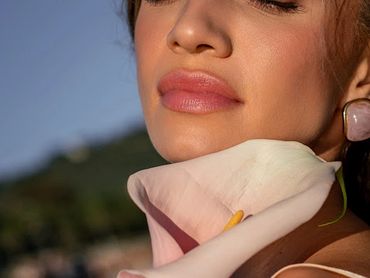 Close-up of a woman's lips and chin holding a white flower.