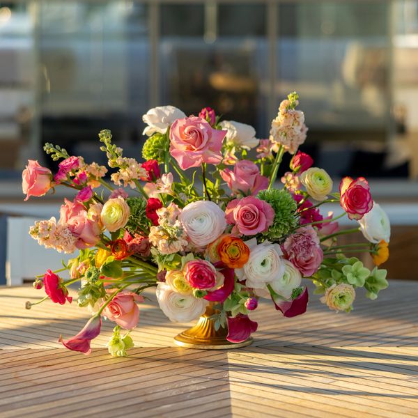 Colorful floral arrangement in a golden vase on a wooden table.