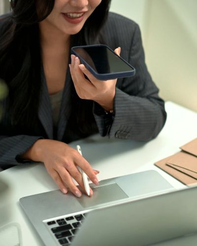 Woman speaking on phone while working on laptop.