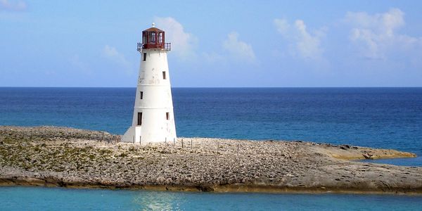 A lighthouse on an island with a storm brewing on the horizon.