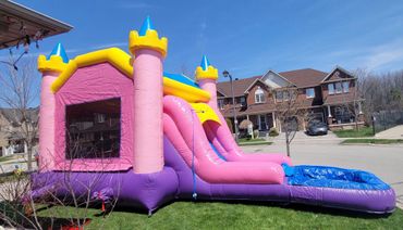 Colorful inflatable bounce house with slide set up in a suburban yard.