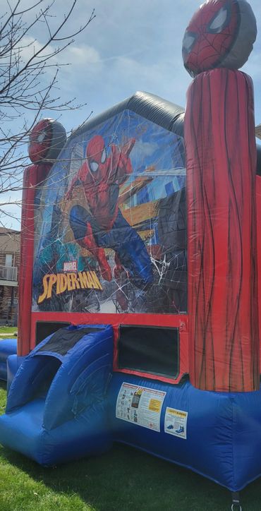 Spider-Man themed inflatable bounce house outdoors on grass.