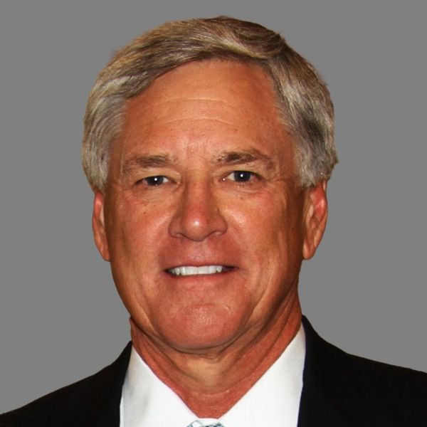 Professional portrait of a middle-aged man with gray hair in formal attire.
