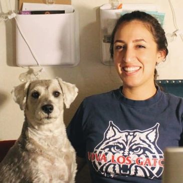 Smiling woman and a white dog sitting together indoors.