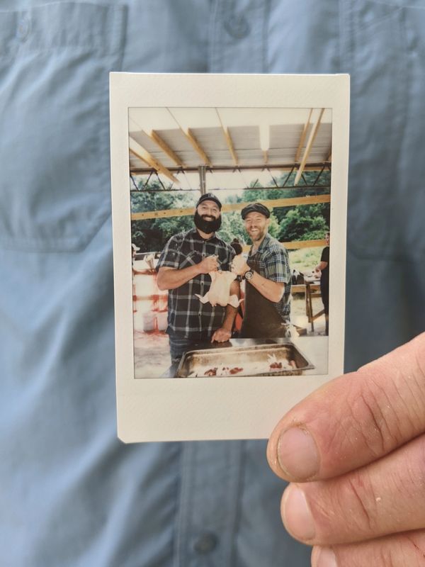 Two men holding a chicken.