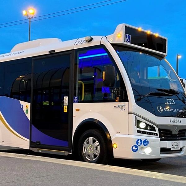 A small transit bus parked at dusk with blue and white colors.