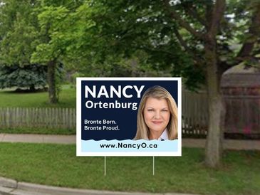Political campaign sign for Nancy Ortenburg in a grassy yard.