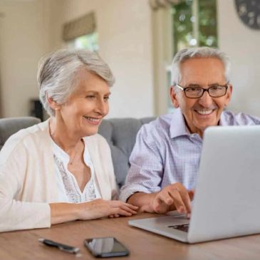 Smiling elderly couple using a laptop together.