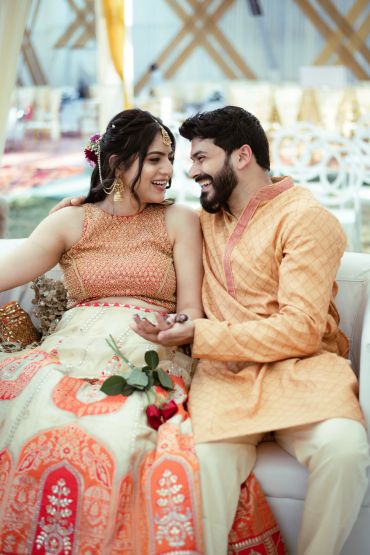 A joyful couple dressed in traditional Indian attire sharing a happy moment.