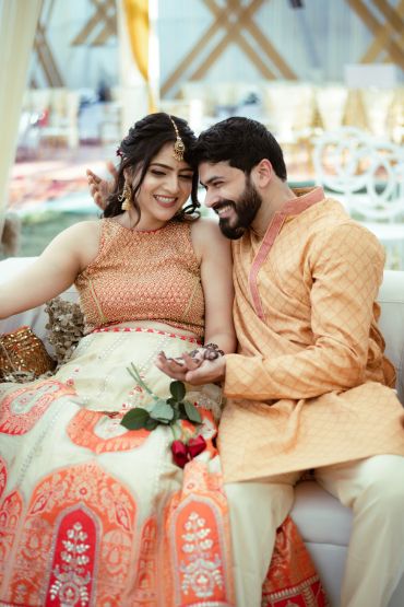 A joyful couple dressed in traditional Indian attire sharing a happy moment.