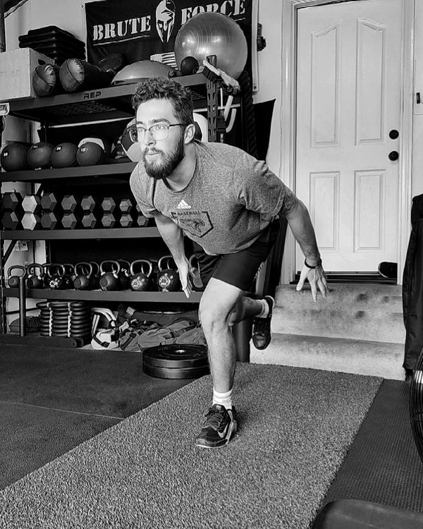 Man balancing on one leg in a gym setting.