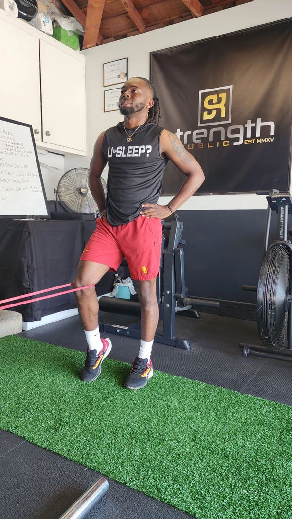 Man exercising with resistance band in a gym.