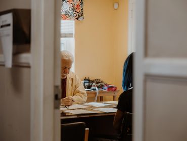 Elderly man and woman engaged in paperwork at a table in a cozy room.