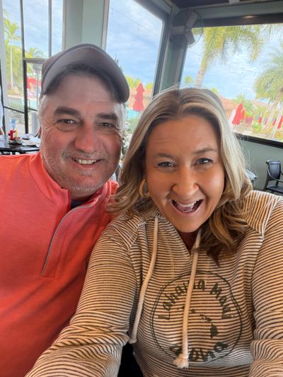 Happy couple smiling inside a bright restaurant with outdoor view.