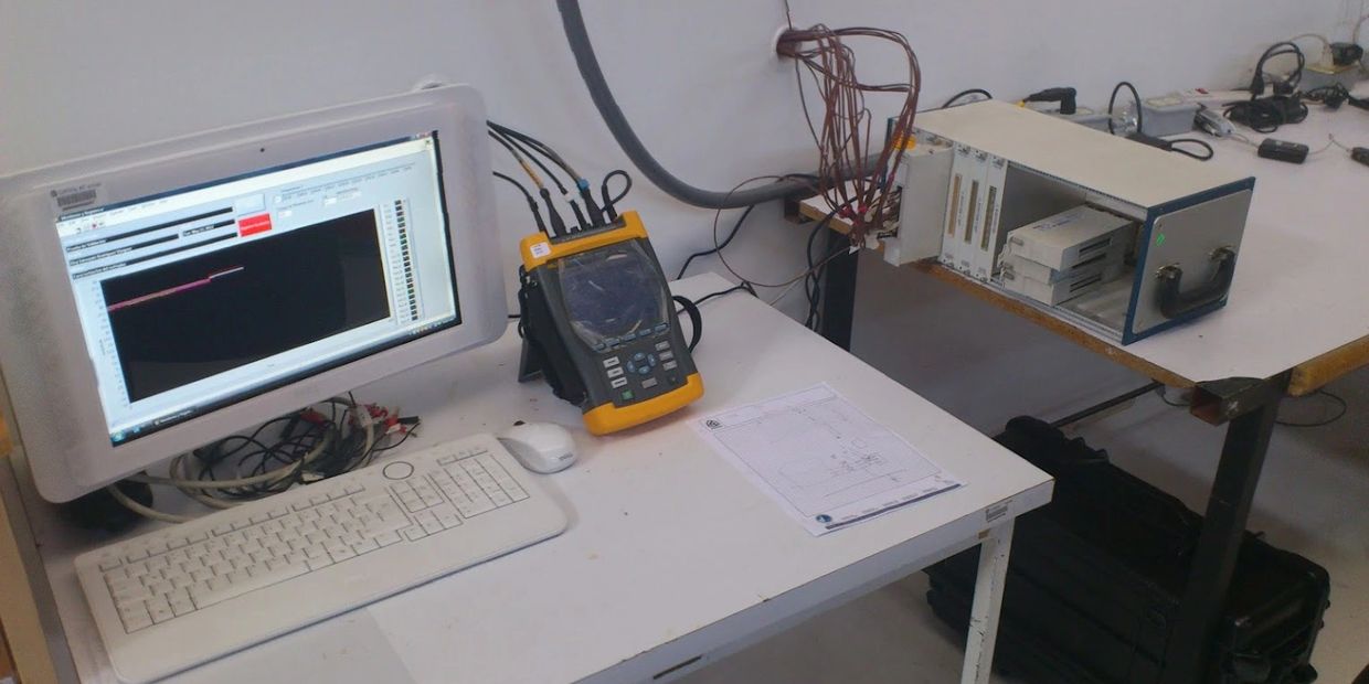 A computer setup with diagnostic and testing equipment on a white desk.