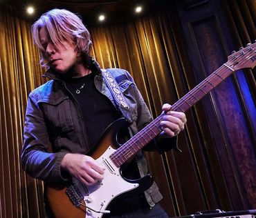 Musician playing electric guitar on stage.
