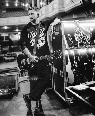Musician with guitar backstage in black and white photo.