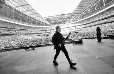 Musician walking on stage in a packed stadium.