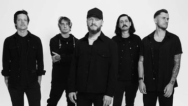 A five-member band in black outfits against a white background.