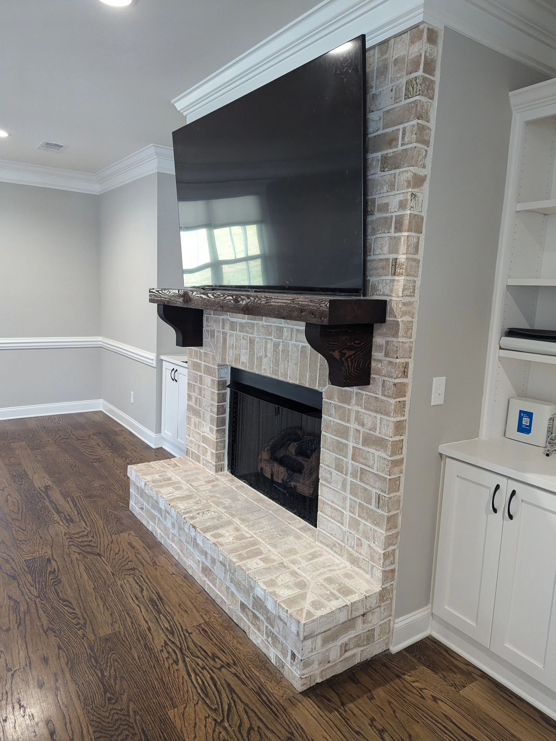 An 85-inch TV Mounted above the fireplace on a brick wall