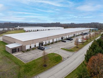 Aerial view of a large industrial warehouse with adjacent parking and road.