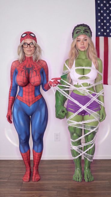 Two women dressed as Spider-Man and Hulk, with the Hulk wrapped in white string.