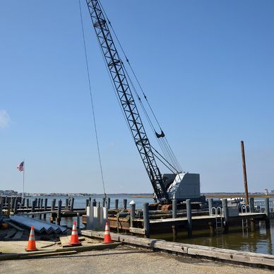 Construction crane on a dock by the water under a clear sky.