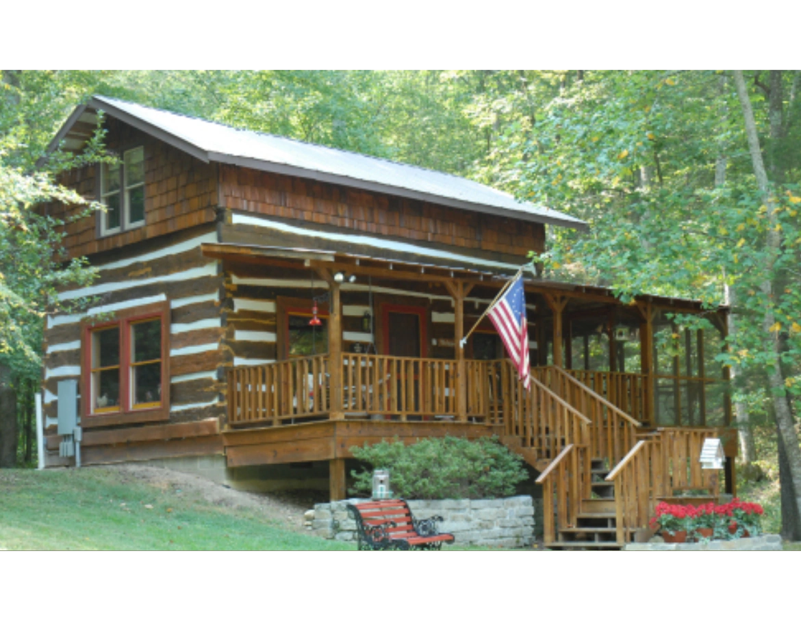Cozy log cabin with an American flag and a wooden porch.