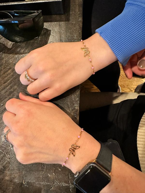 Matching butterfly bracelets on two wrists.