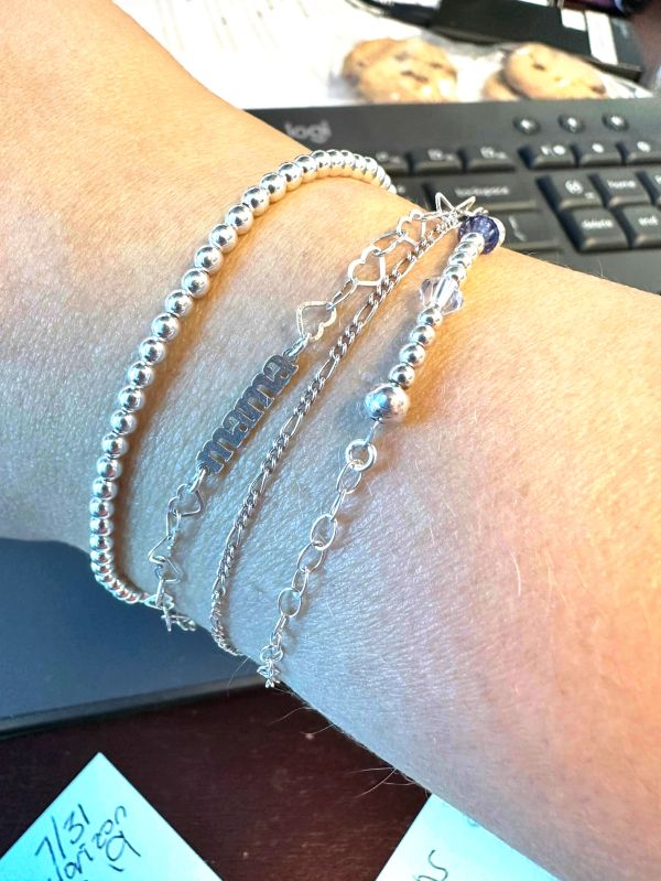 Silver bracelets on wrist with keyboard and cookies in background.