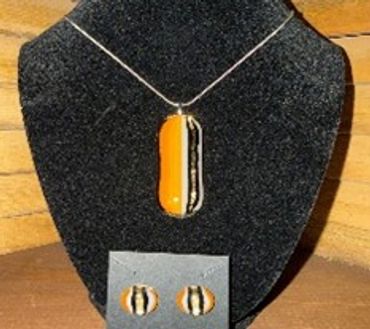 Orange and black striped pendant necklace with matching earrings on display.