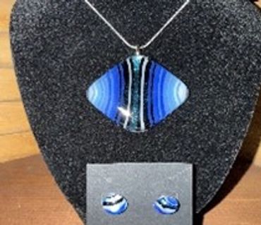 Blue and black striped glass pendant with matching earrings on display.