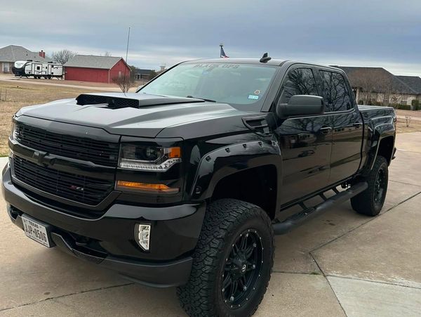 Black lifted Chevrolet pickup truck with aggressive tires.