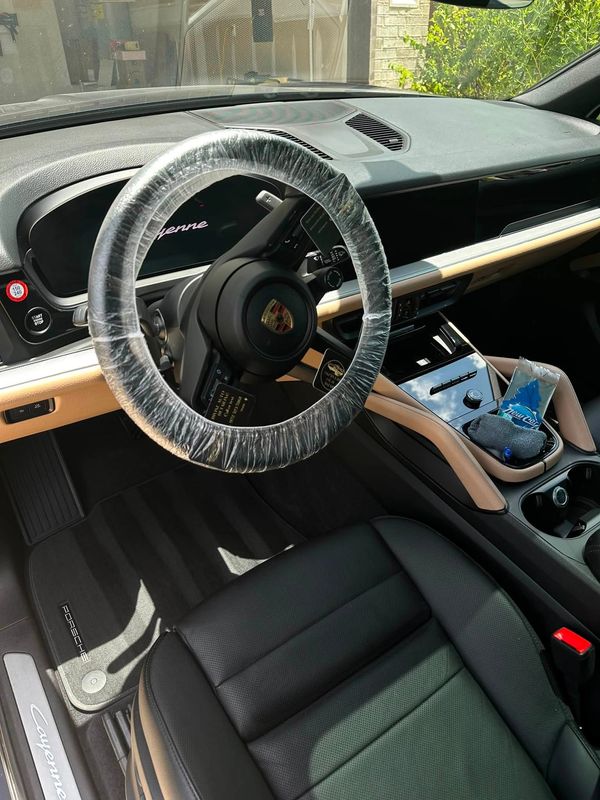 Interior of a Porsche Cayenne with a plastic-covered steering wheel.