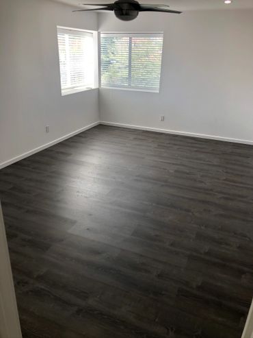 Empty room with dark wood flooring and white walls.