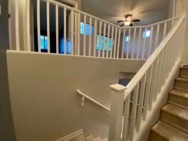 Indoor staircase with white railings and beige carpet.
