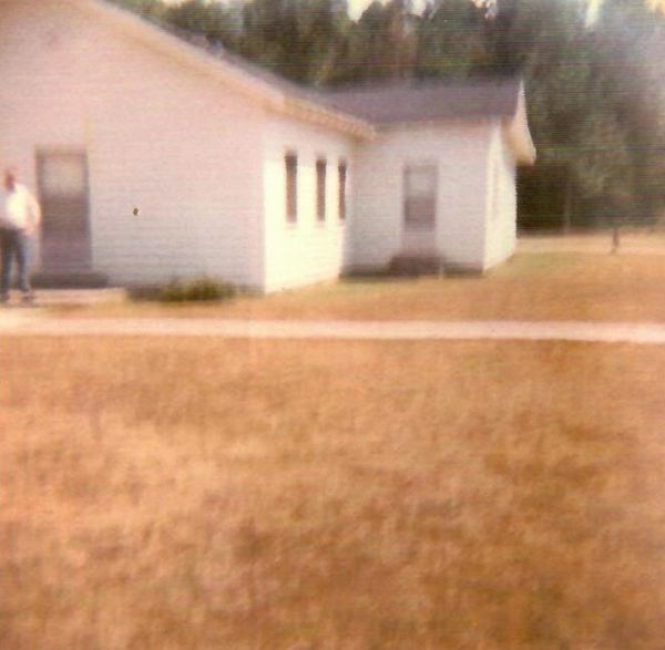 A blurry image of a white building with a person standing near the door.