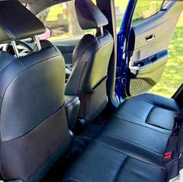 Interior view of a car showing black leather seats and an open door.