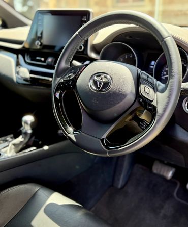 Interior of a Toyota car focusing on the steering wheel and dashboard.